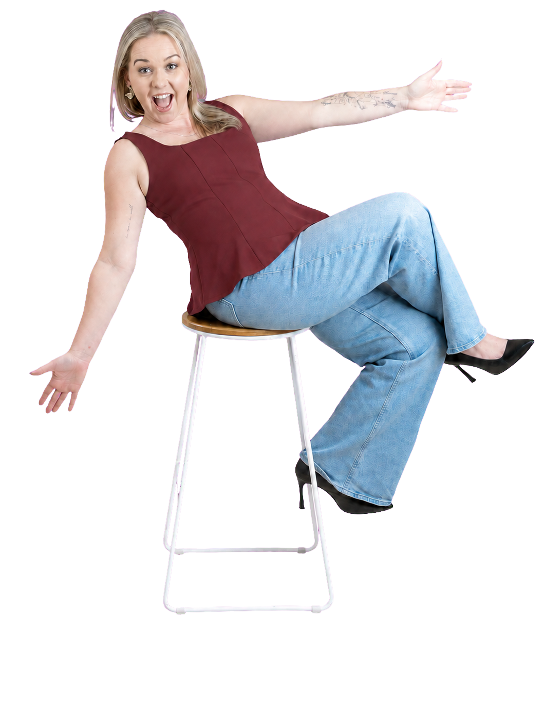Cassandra Gore, Melbourne HR consultant, smiling and gesturing with an outstretched arm while seated on a stool.